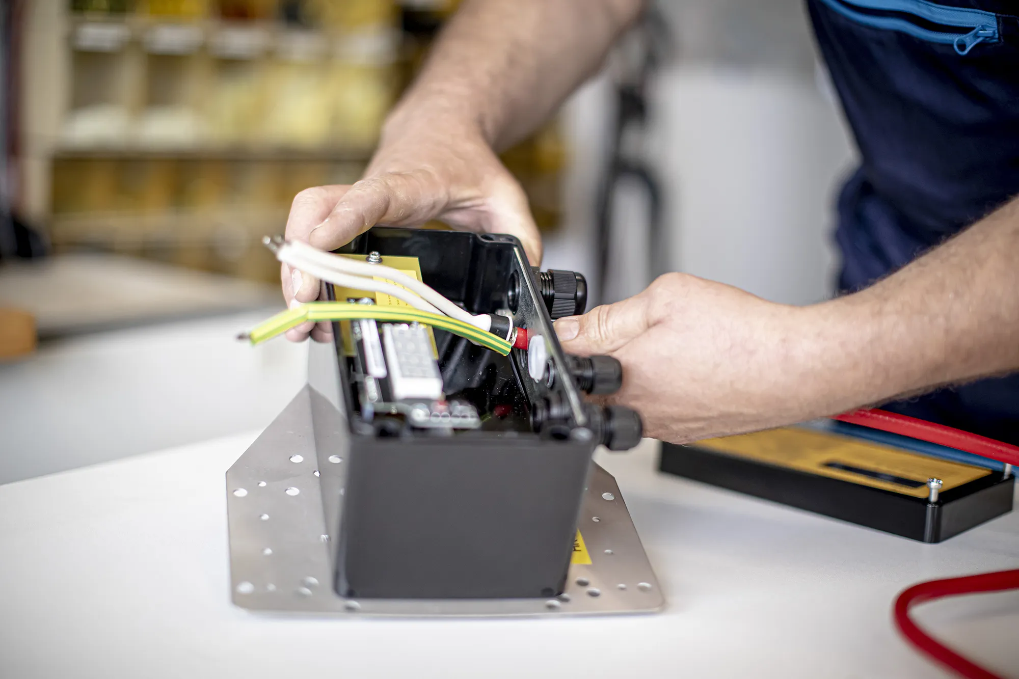 Ein Mann hantiert an einer Schachtel, in der Kabel eingebunden sind
