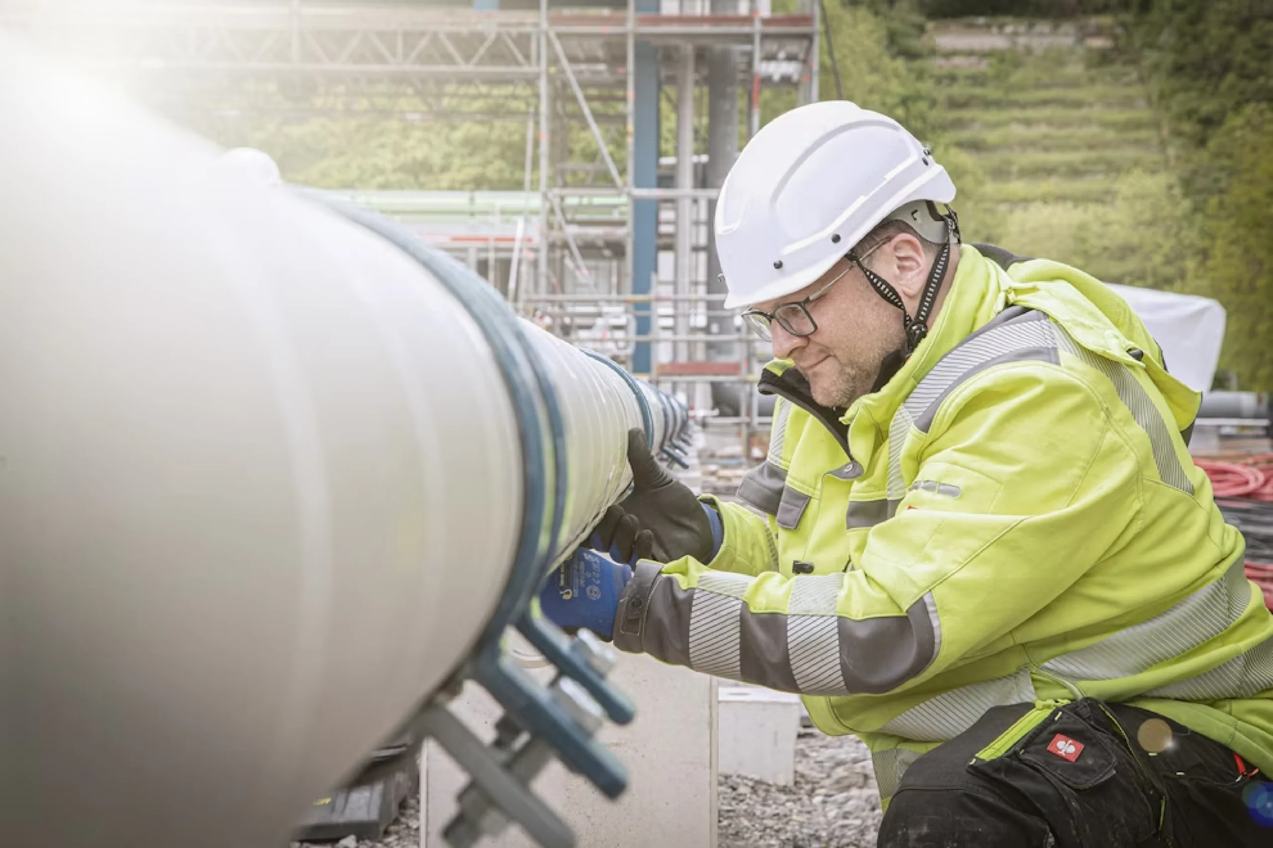 Ein Mann baut auf einer Baustelle an einem breit verlegtem Rohr