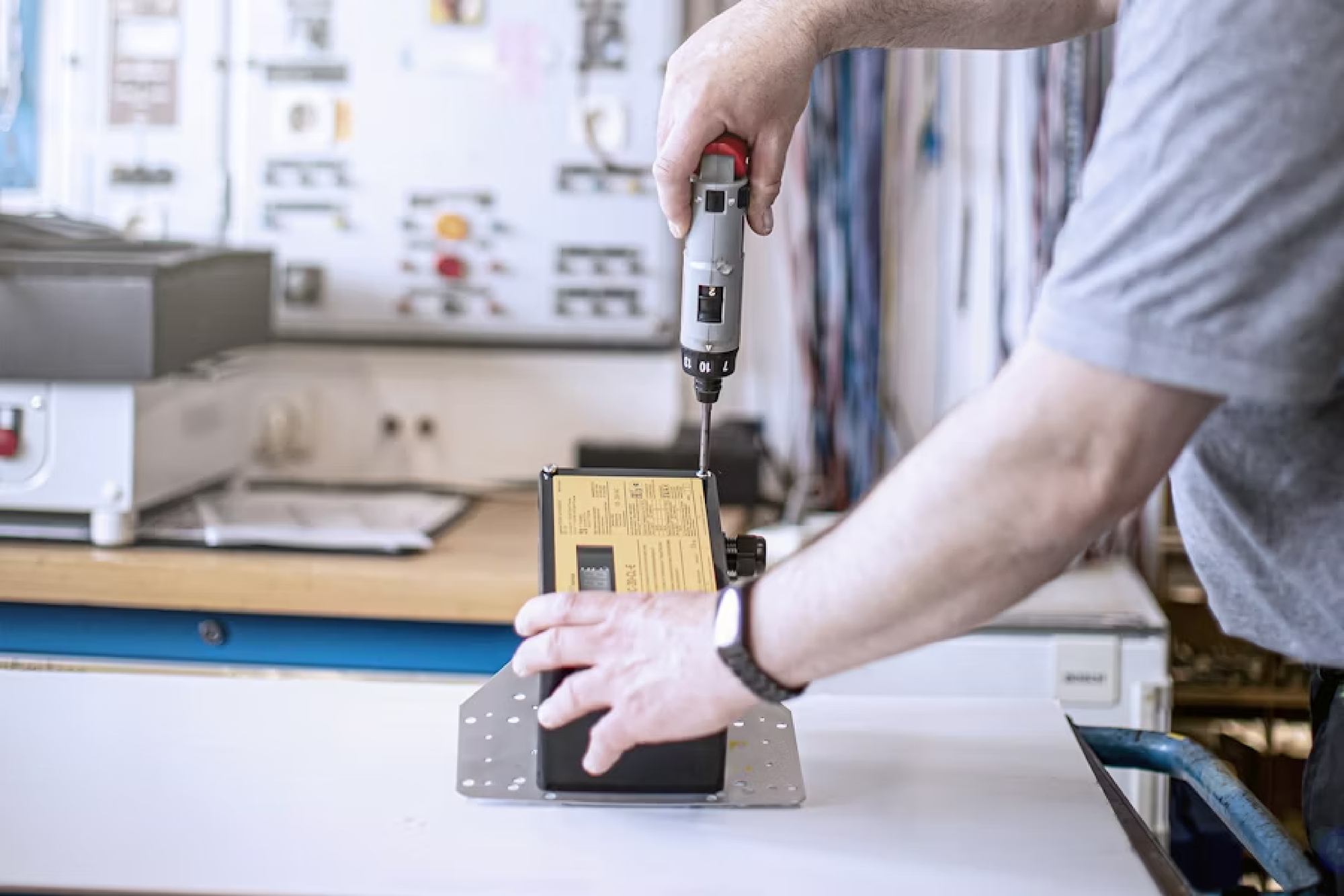 Eine Person bohrt Schrauben in ein Gerät rein