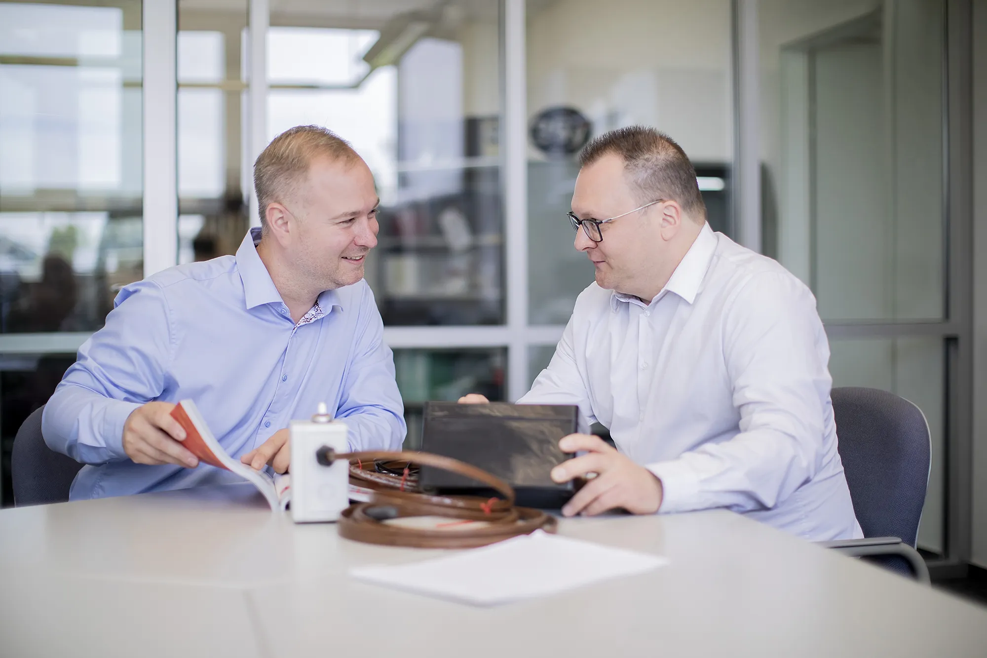 Ein Gespräch zwischen zwei Männern in Hemden an einem Tisch